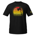 A black short-sleeve t-shirt with a retro sunset graphic on the chest featuring a palm tree and the text “We’ll @?#! You First” and the below that the word “LAVENALIDA"
